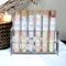 Assorted bath salts by Whole Self Aromatherapy in test tubes on elegant white linen, with a candle softly glowing in the background.